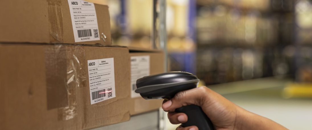 Close up of black woman worker scanning packages in a large storehouse, registering airway bills shipment details within industrial depot records. Using scanner for order fulfillment.